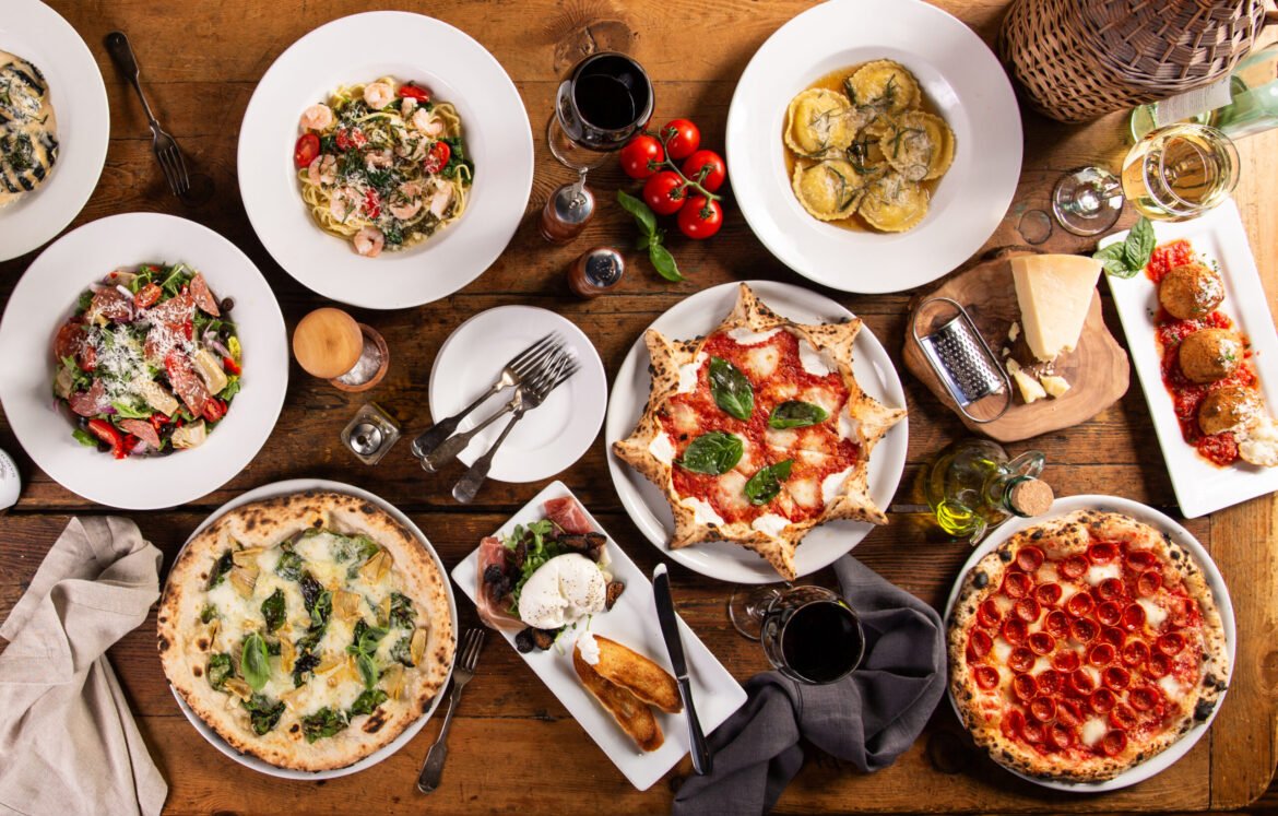 Big dinner table with italian food, pizzas and pastas, appetizers and wine