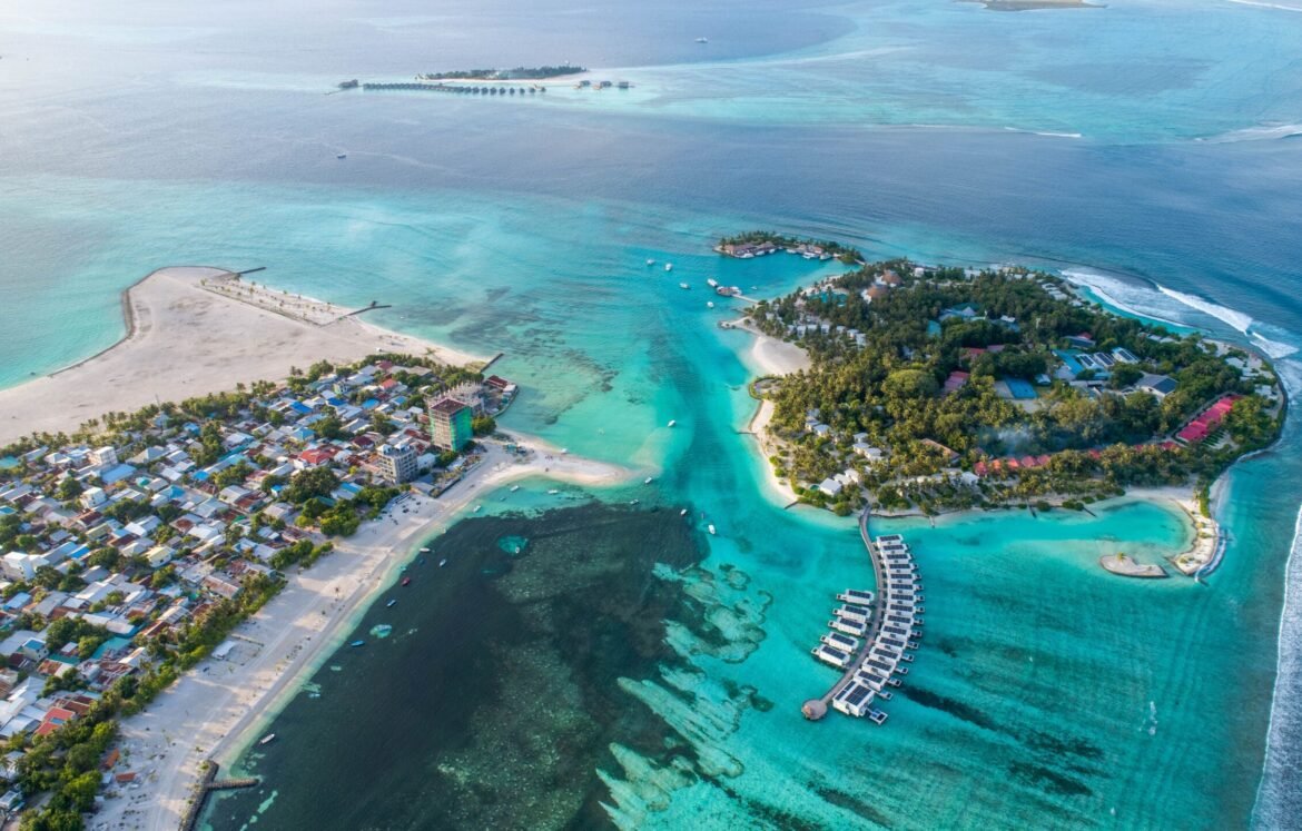 Aerial view of a tropical island with clear turquoise waters and overwater bungalows in the Maldives An aerial view of a tropical island with clear turquoise waters and overwater bungalows in the Maldives