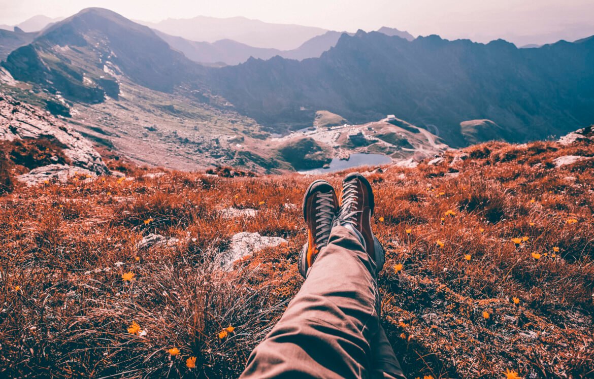 Legs of traveler sitting on a high mountain top in travel Legs of traveler sitting on a high mountain top in travel. Freedom concept