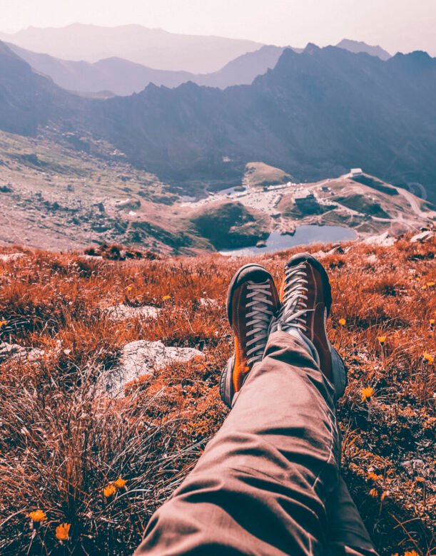Legs of traveler sitting on a high mountain top in travel. Freedom concept