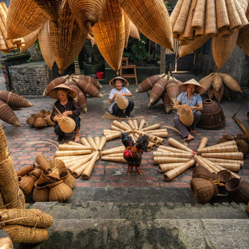 Old Vietnamese female craftsman making the traditional bamboo fish trap or weave at the old traditional house in Thu sy trade village, Hung Yen, Vietnam, traditional artist concept