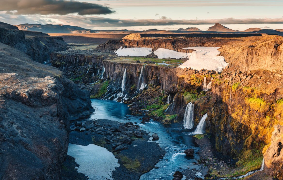 Sunset over Sigoldugljufur with tiny waterfall flowing in canyon Beautiful sunset over Sigoldugljufur with tiny waterfall flowing in canyon on Icelandic Highlands in summer at Iceland