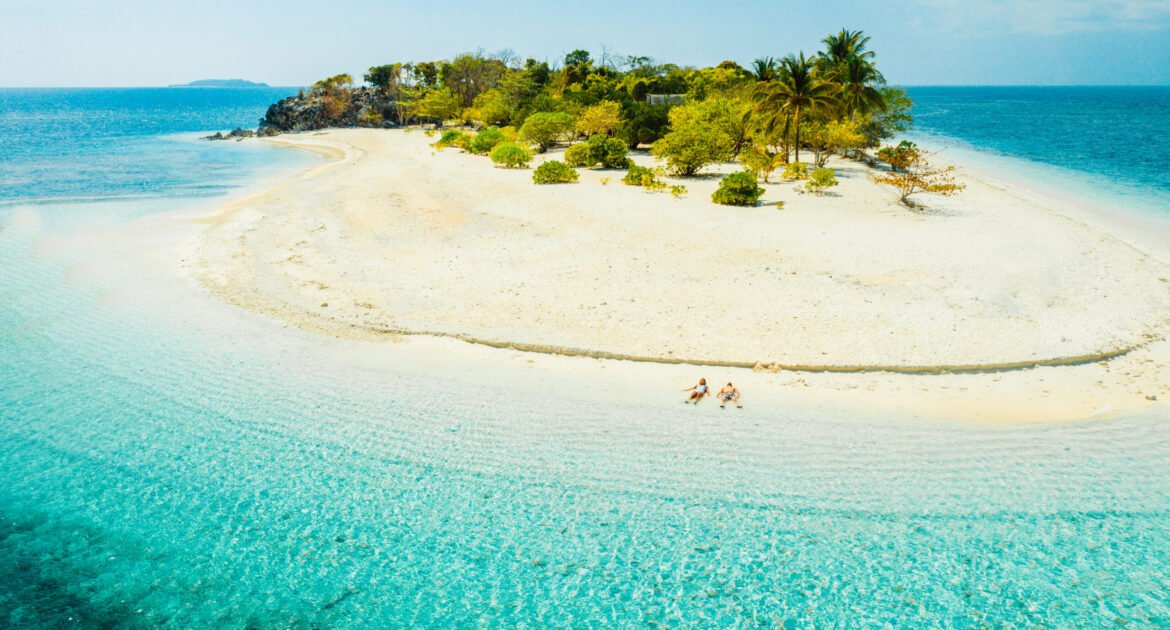 Couple on a tropical beach with blue water and palm trees - Coron, Philippines