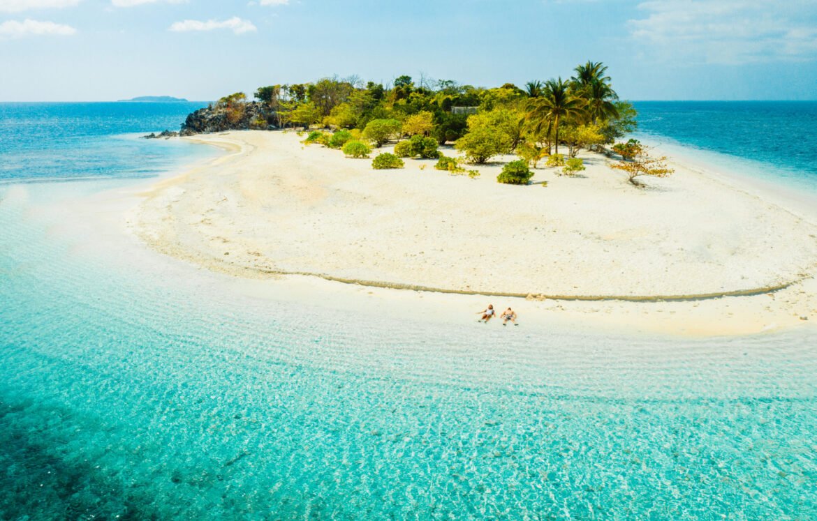 Couple on a tropical beach with blue water and palm trees - Coron, Philippines