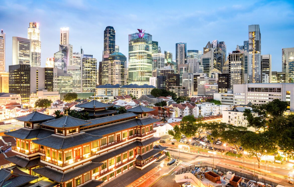 High view of Singapore skyline with skyscrapers and Tooth Relic Temple at blue hour - World famous top south east Asia destinations - City panorama on vivid warm filter with nightscape color tones